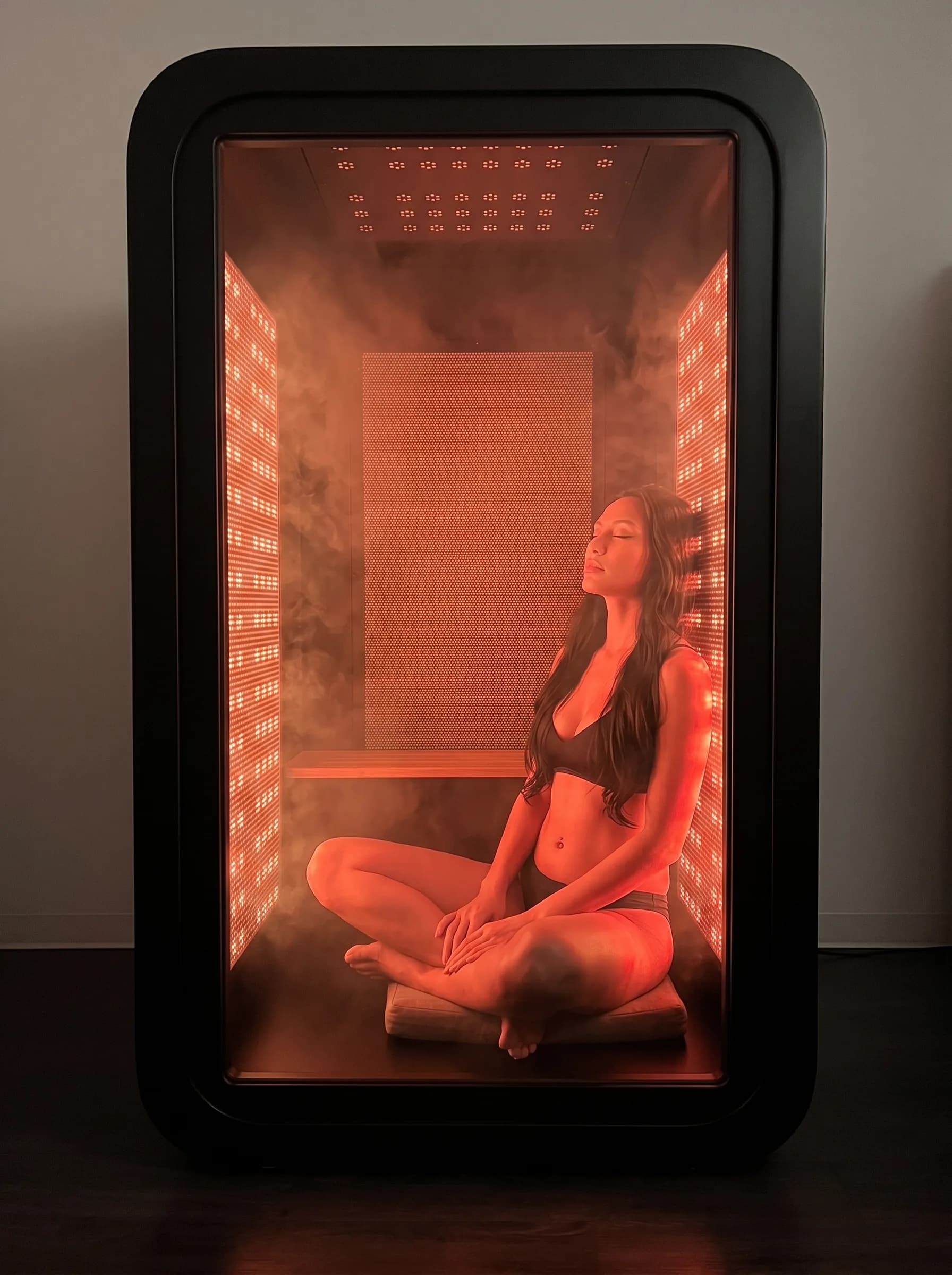 Personne installée dans la cabine Halocab, baignée d'une lumière rouge et ambrée